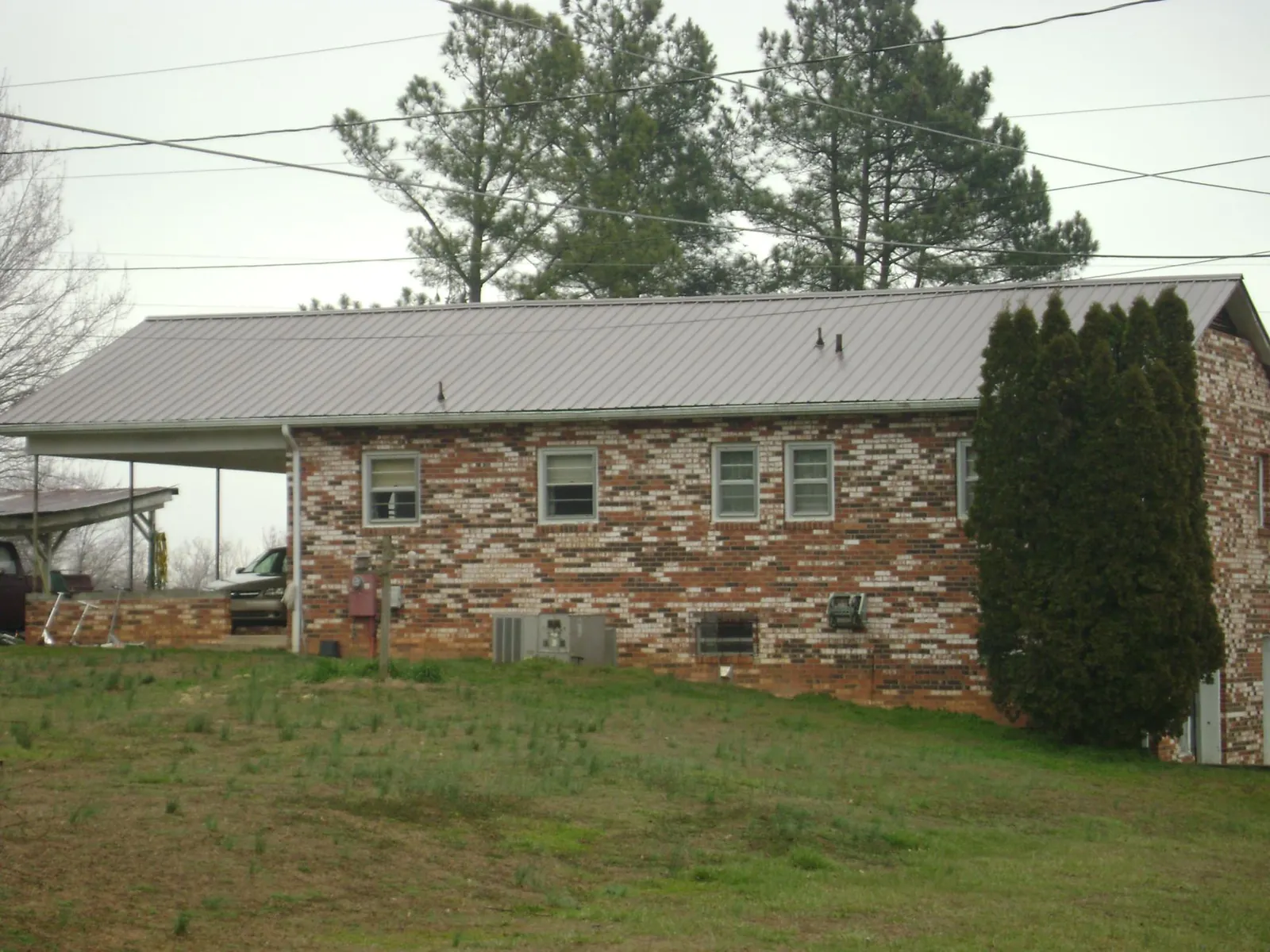Gray metal roof on a brick split level home with a carport in Freeport